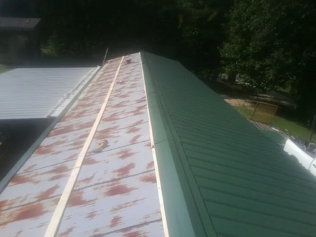 Old rusted panels beside newly installed green metal roofing — Wind Damage Roof Repair by Roofing Brothers in Roans Prairie