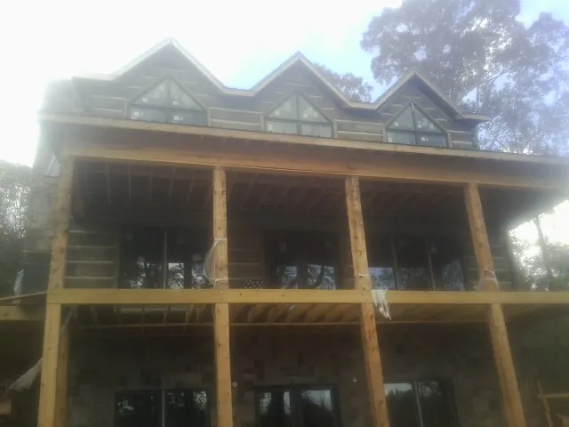 Dormers and porch framing on a large log home under construction — Roof Coating work by our crew in Roans Prairie