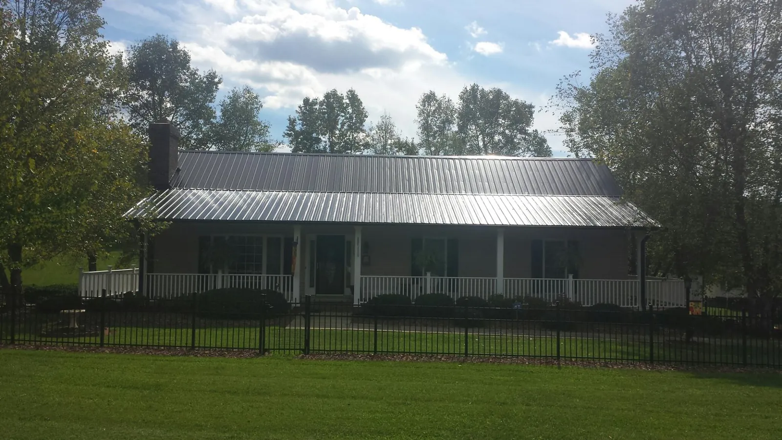 Gray metal roof on a brick ranch with a full width front porch — Gutter Guard Installation work by our crew in Roans Prairie