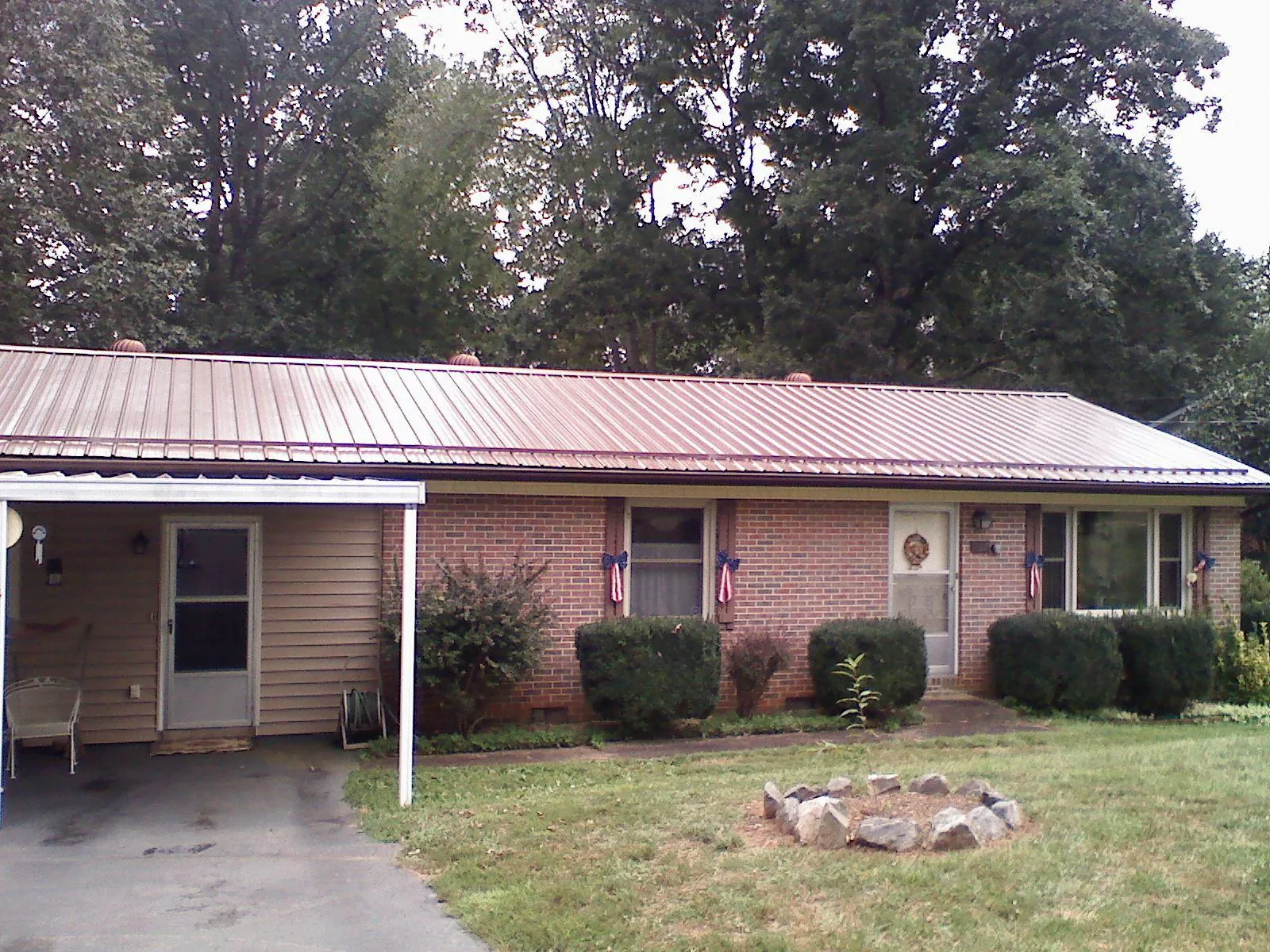 Bronze metal roof and carport on a brick ranch home — Roof Repair work by our crew in Roans Prairie