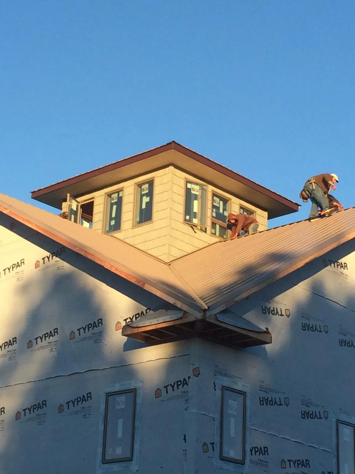 Roofers working around a rooftop cupola on a new metal roof at sunset — Roof Waterproofing in Roans Prairie by Roofing Brothers